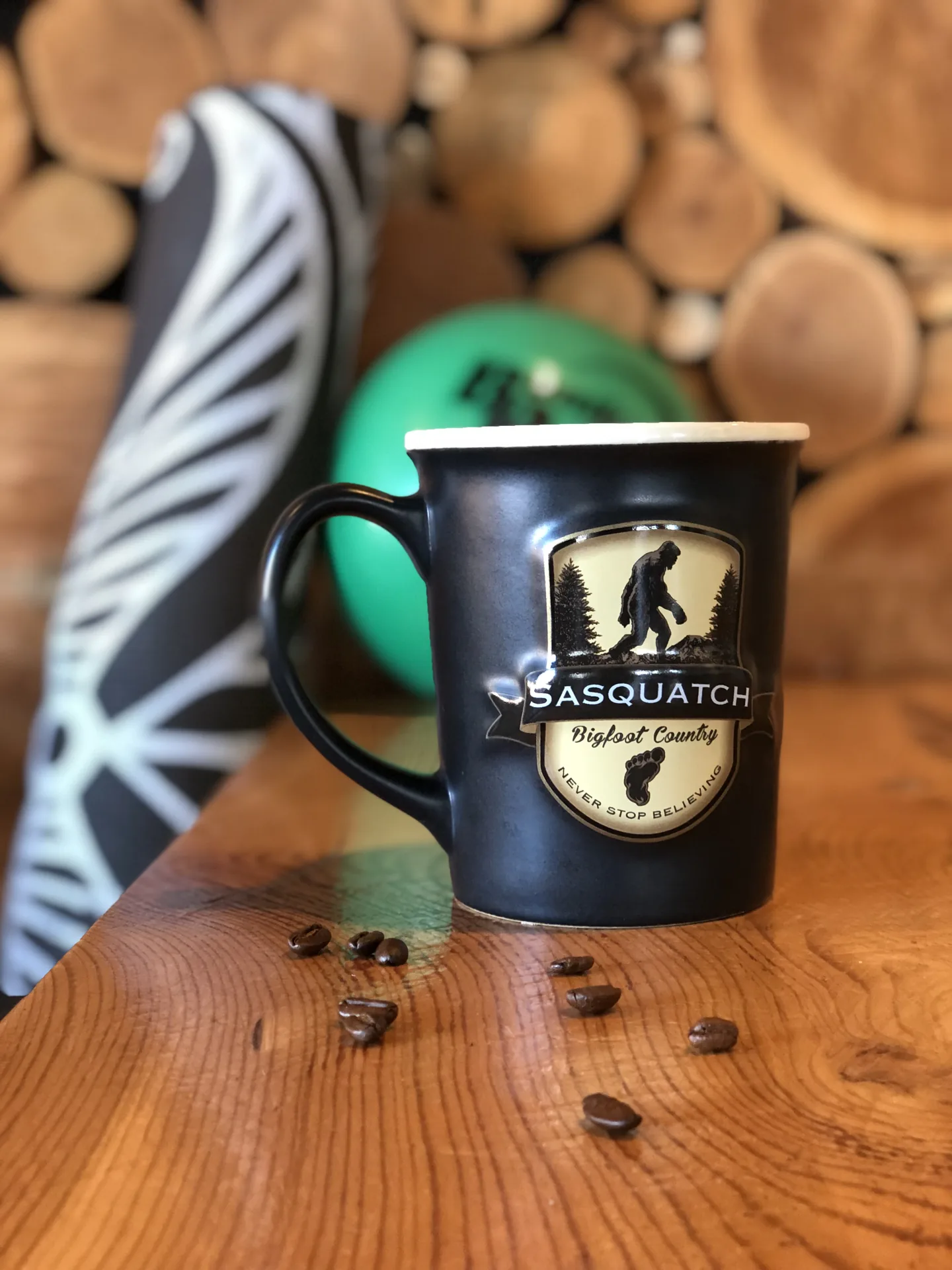 A coffee mug on a wooden table at Black Bull Coffee, with a foam roller and an exercise ball behind it