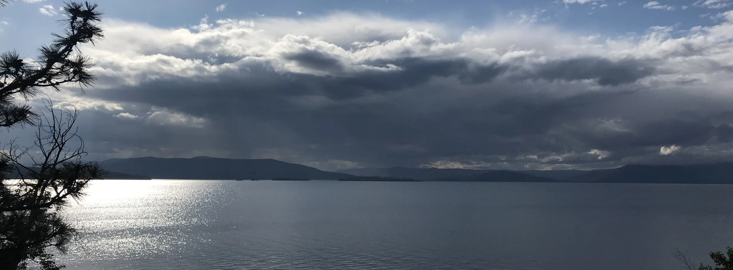 A lake and distant hills under breaking storm clouds